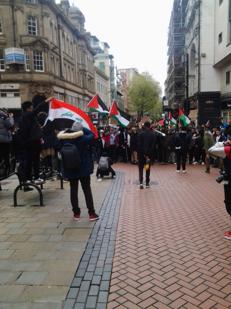 Crowd approaching Victoria square with Palestine flags. Protesters are facing the camera. 
