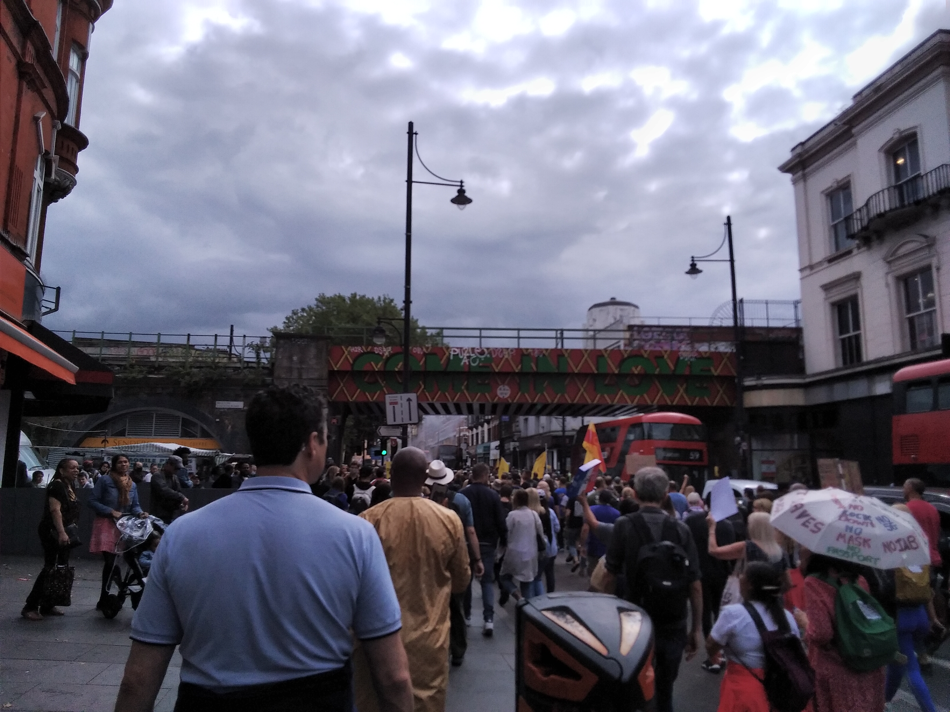Protesters going under a bridge reading 'Come in Love', London.