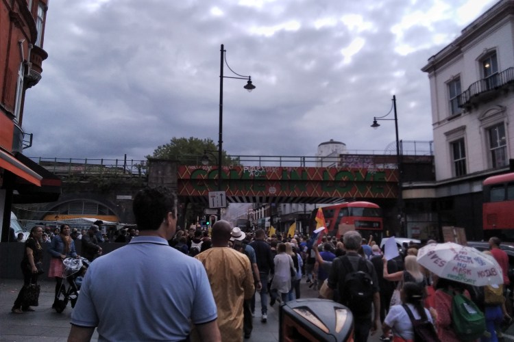 Protesters going under a bridge reading 'Come in Love', London.