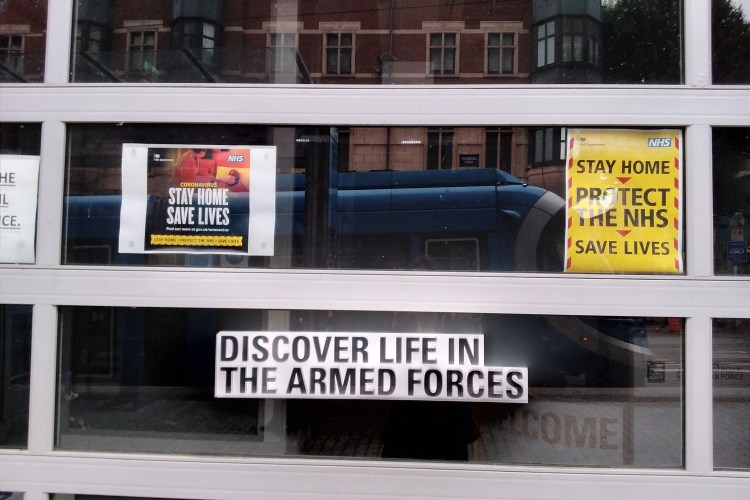 Army recruitment hub. Window reads "Discover Life in the Armed Forces". Tacked sign above it reads "Stay Home, Save Lives"