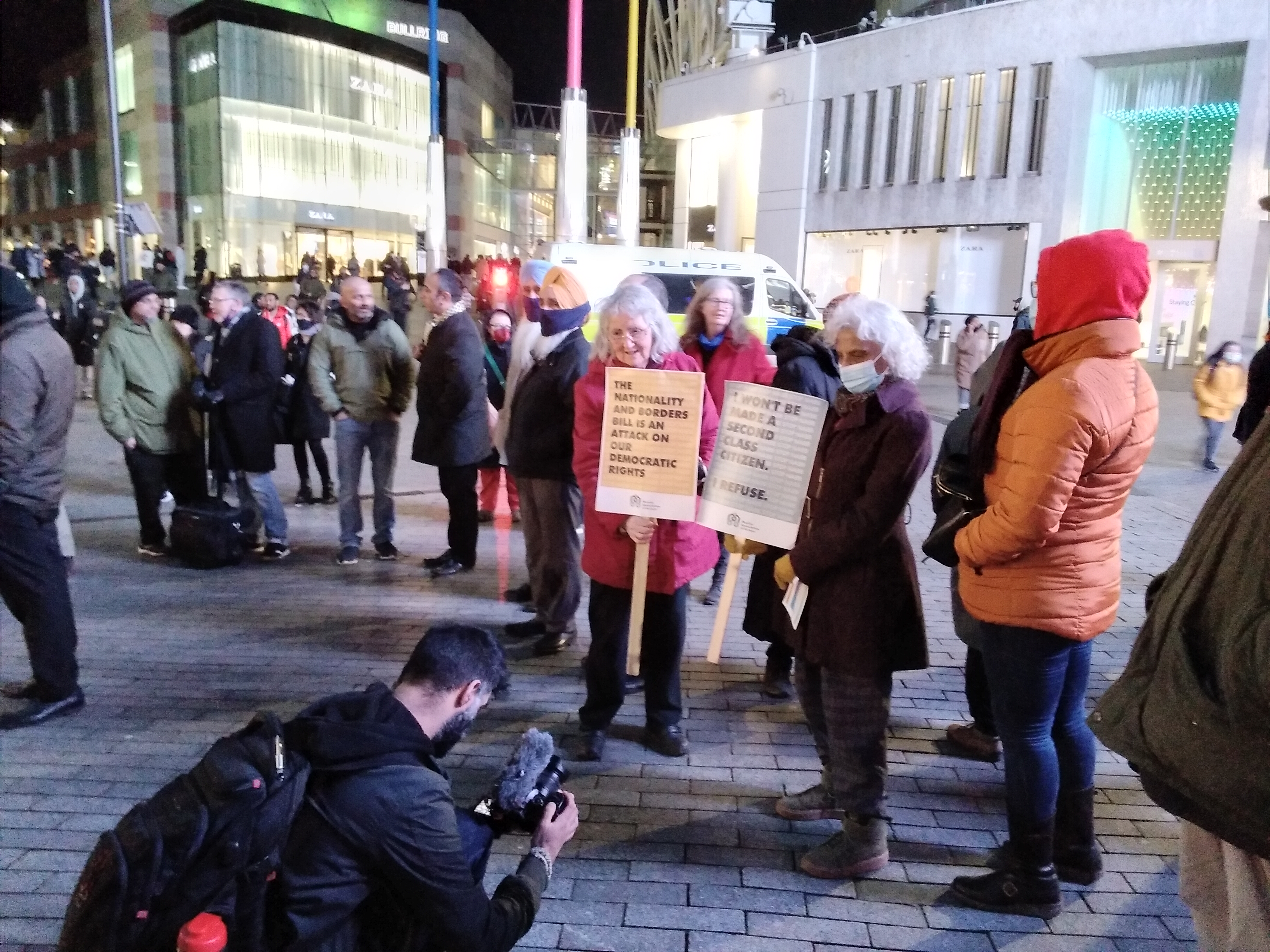 Protesters in a winter evening in Birmingham City Centre. Two older ladies hold signs opposing the Nationality Bill.