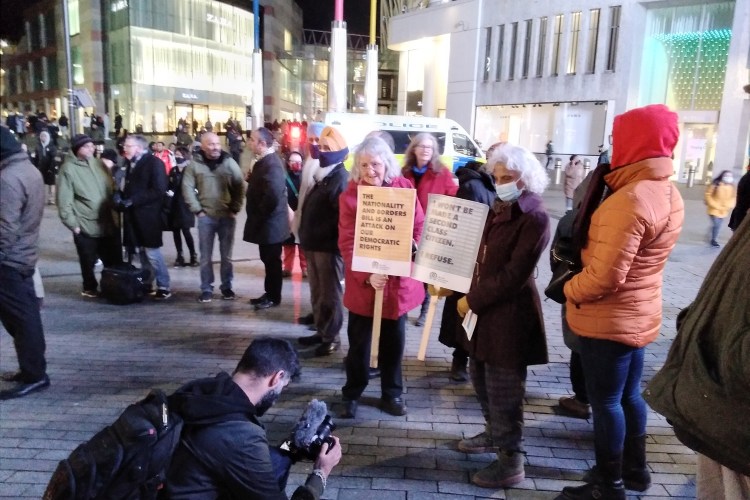 Protesters in a winter evening in Birmingham City Centre. Two older ladies hold signs opposing the Nationality Bill.