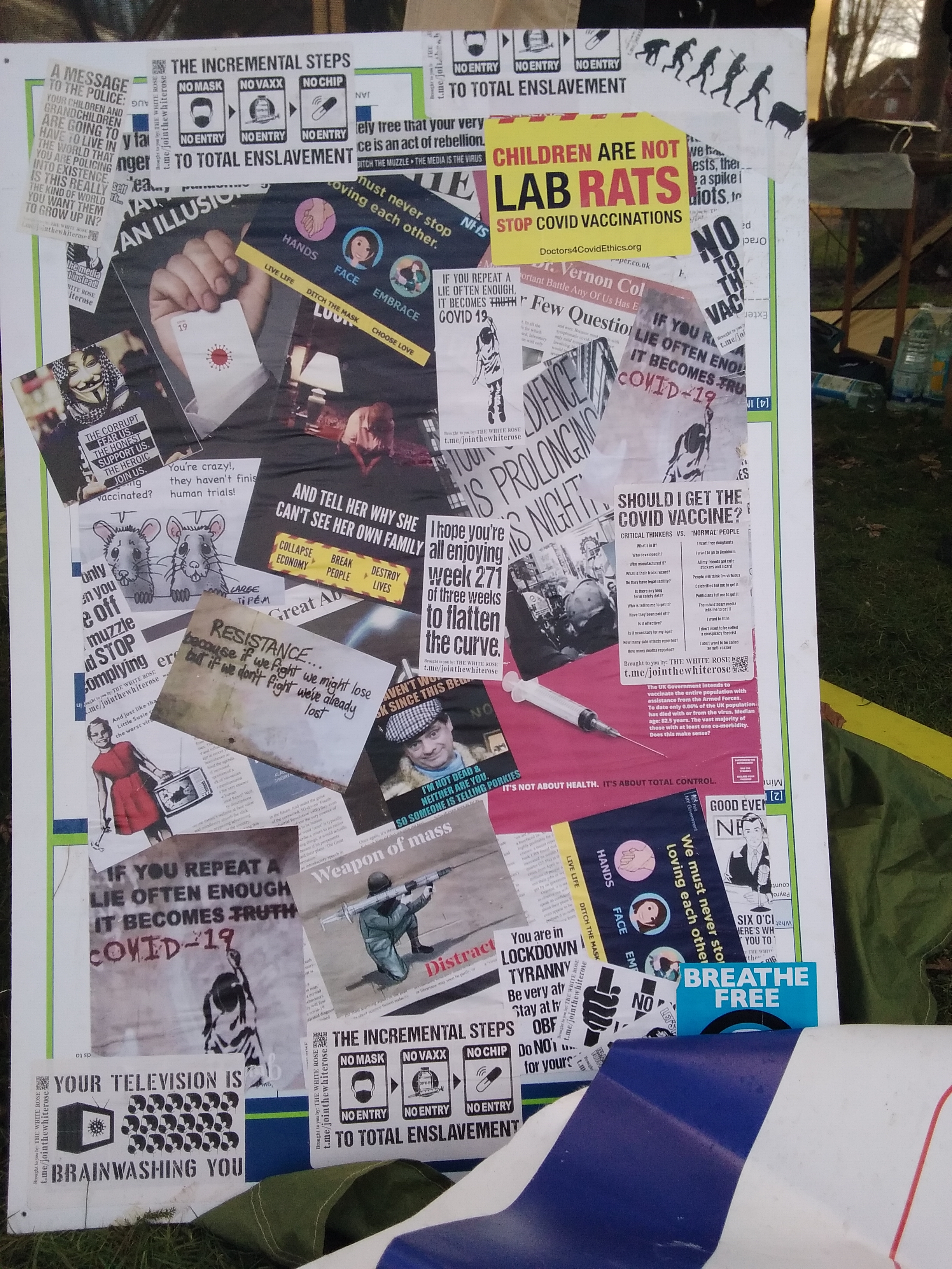 A sign showing a large number of overlapped stickers with messages opposing the Covid 19 narrative.