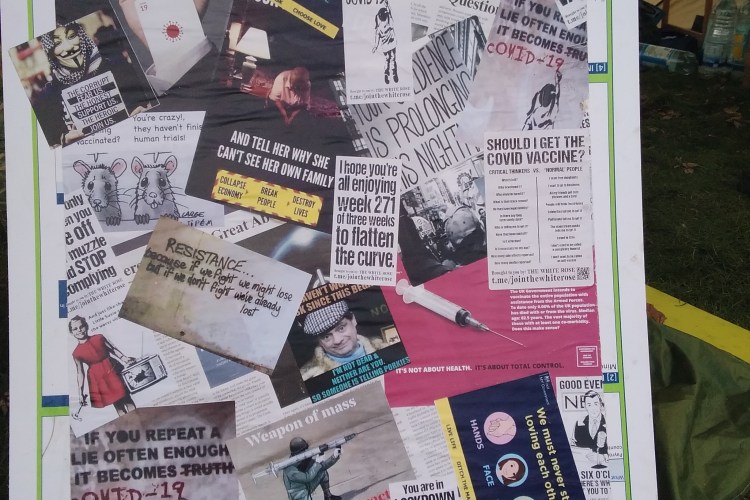 A sign showing a large number of overlapped stickers with messages opposing the Covid 19 narrative.