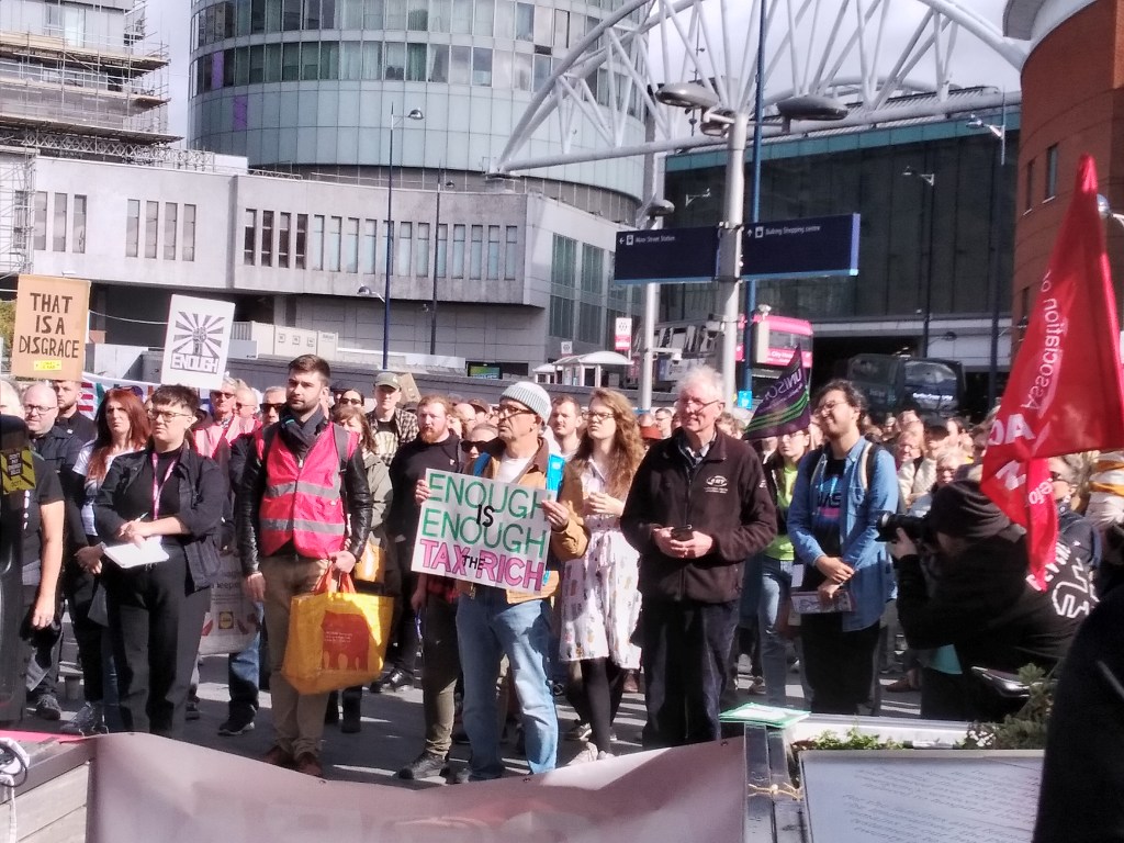 Man holds sign reading ' Enough is Enough, Tax the Rich'