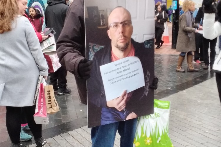 Sign with a man stating he was vaccine injured by the Covid 19 AstraZeneca vaccine, diagnosed with Vaccine Induced Thrombosis Thrombocytopenia.