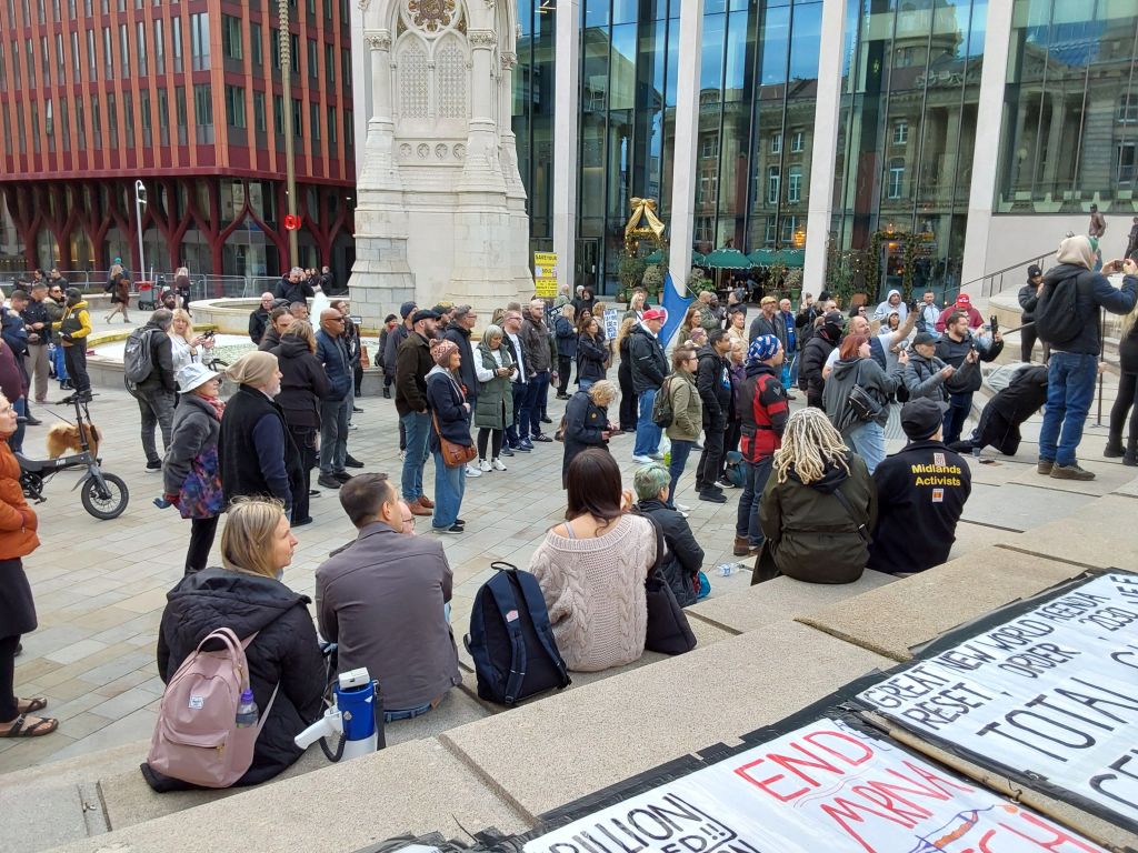 Crowd sitting on steps and standing at the bottom of steps in front of large water fountain