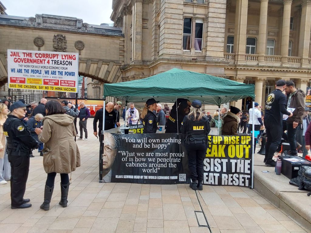 Booth giving out information with quotes from Klaus Schwab on a banner 'You will own nothing and be happy'