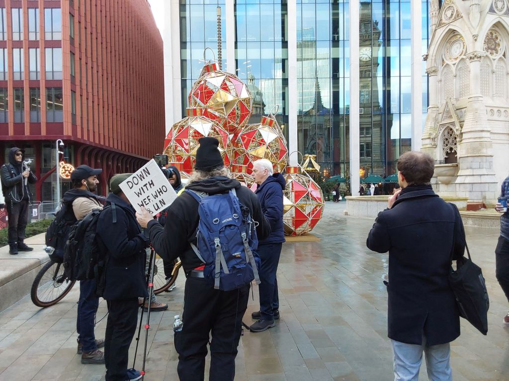 David Icke giving an interview in front of oversized Christmas baubles.